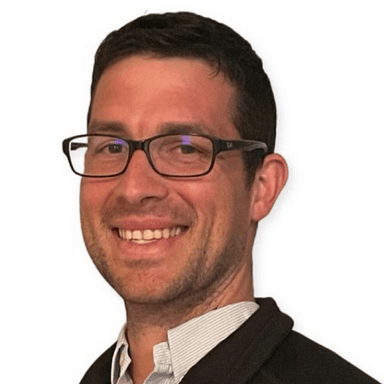 Ben Newell smiling in a blazer and glasses